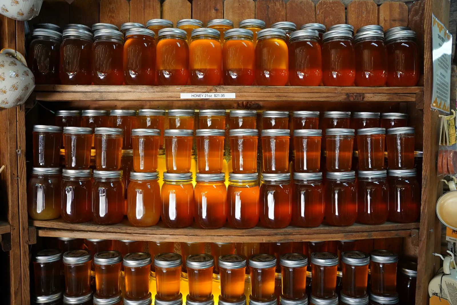 Assorted honey jars displayed on wooden shelves with varied colors and hues.